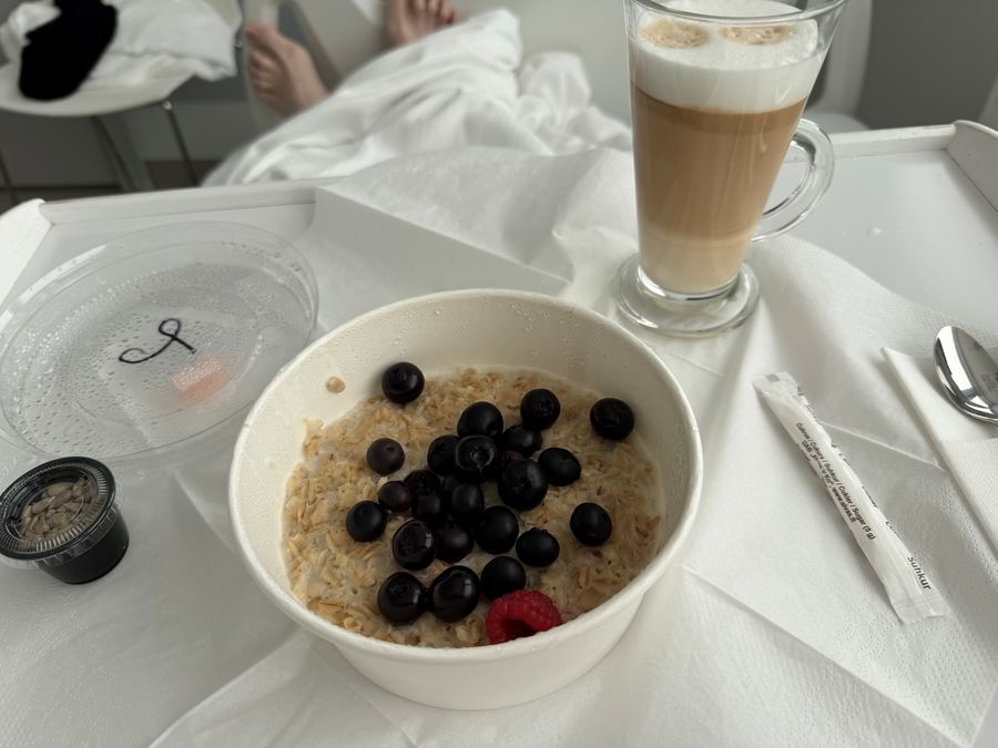 Hospital breakfast tray with porridge, blueberries and a latte