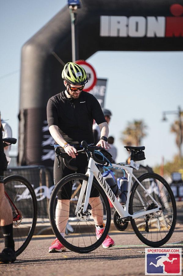 Jamie walking his Canyon into bike check-in under the IRONMAN arch