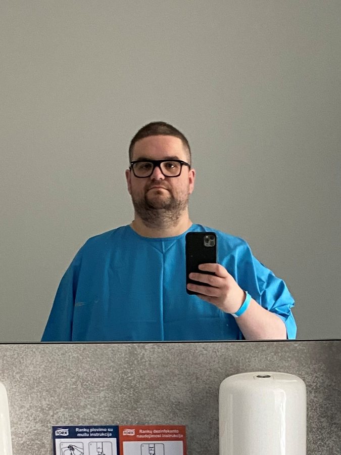 Jamie in a blue hospital gown taking a mirror selfie in September 2022