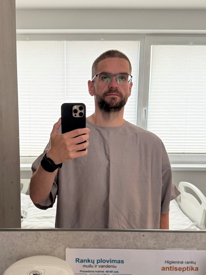 Jamie in a grey hospital gown taking a mirror selfie in August 2026
